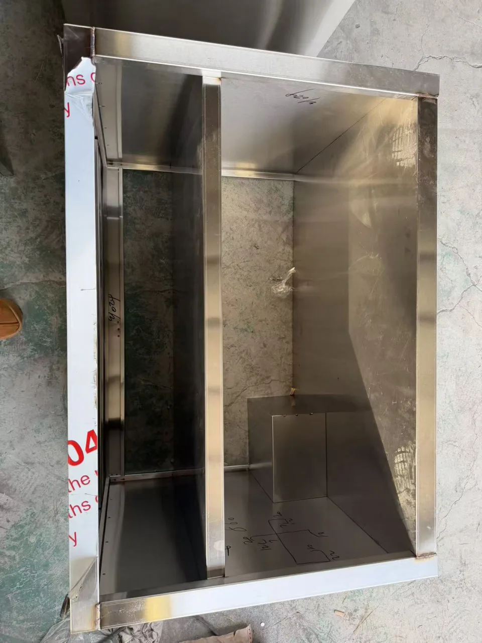 Interior of an unfinished stainless cabinet showing internal panels and cross members