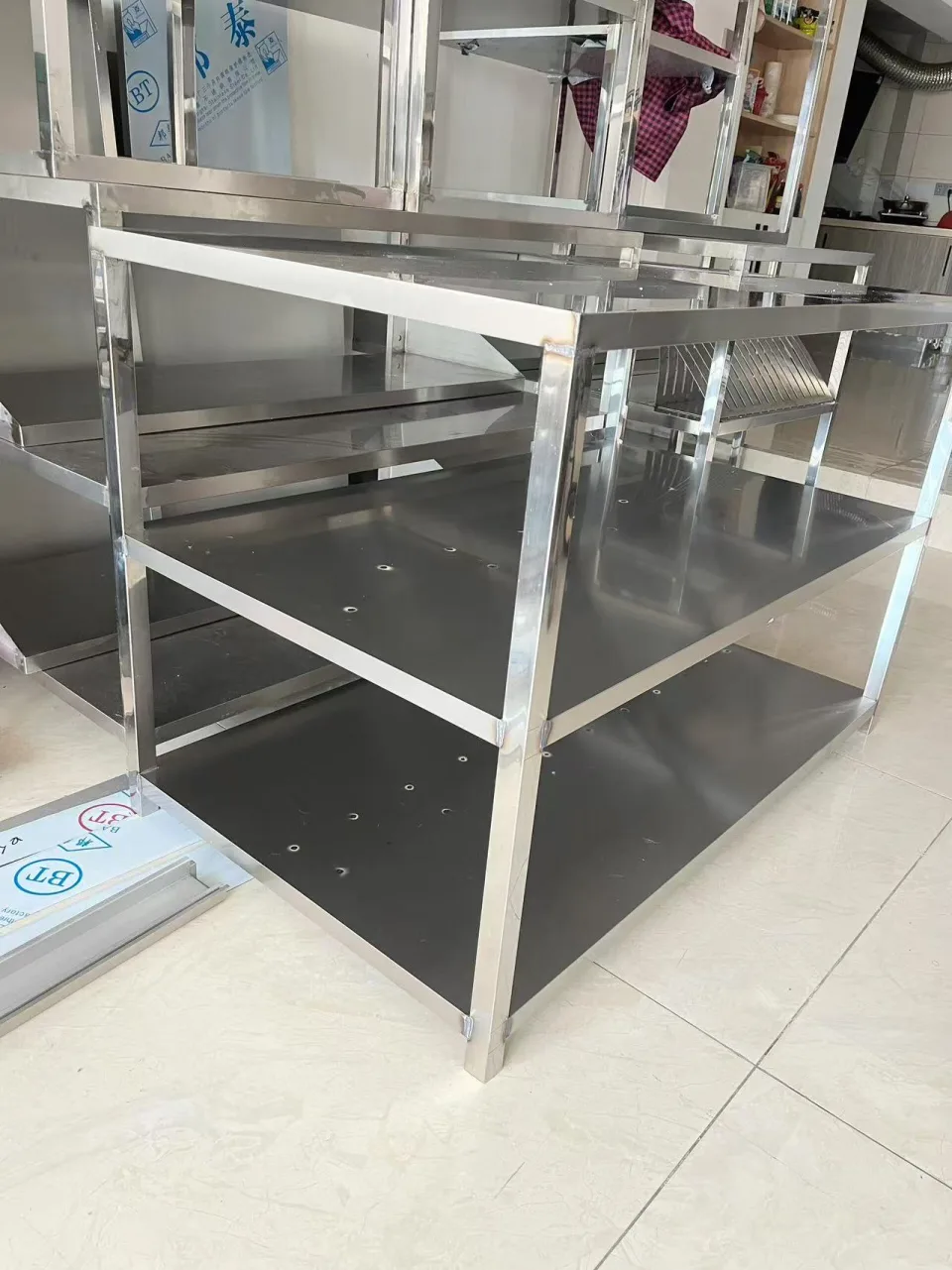 Stainless open storage frame with a top surface, intermediate shelf and lower shelf