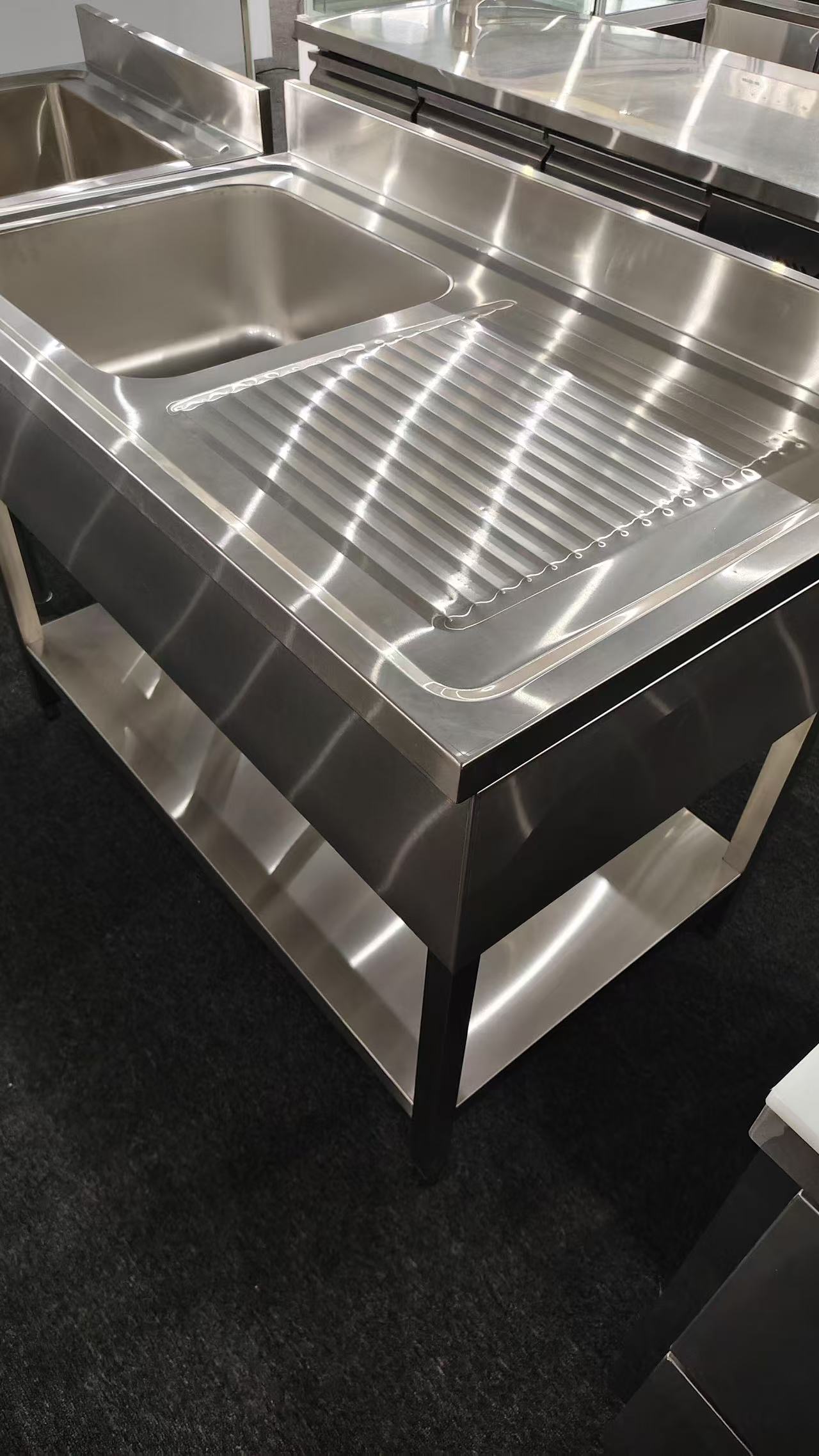 Close view of a stainless steel sink and cabinet fabrication detail in a partner workshop