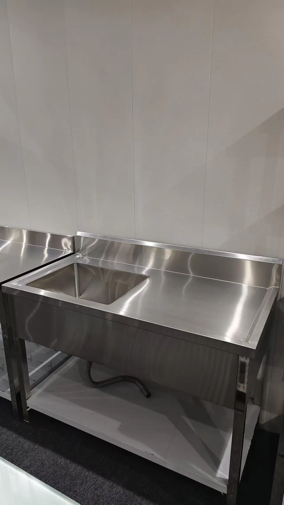 Single-bowl stainless sink bench with an adjacent plain surface, rear upstand and undershelf
