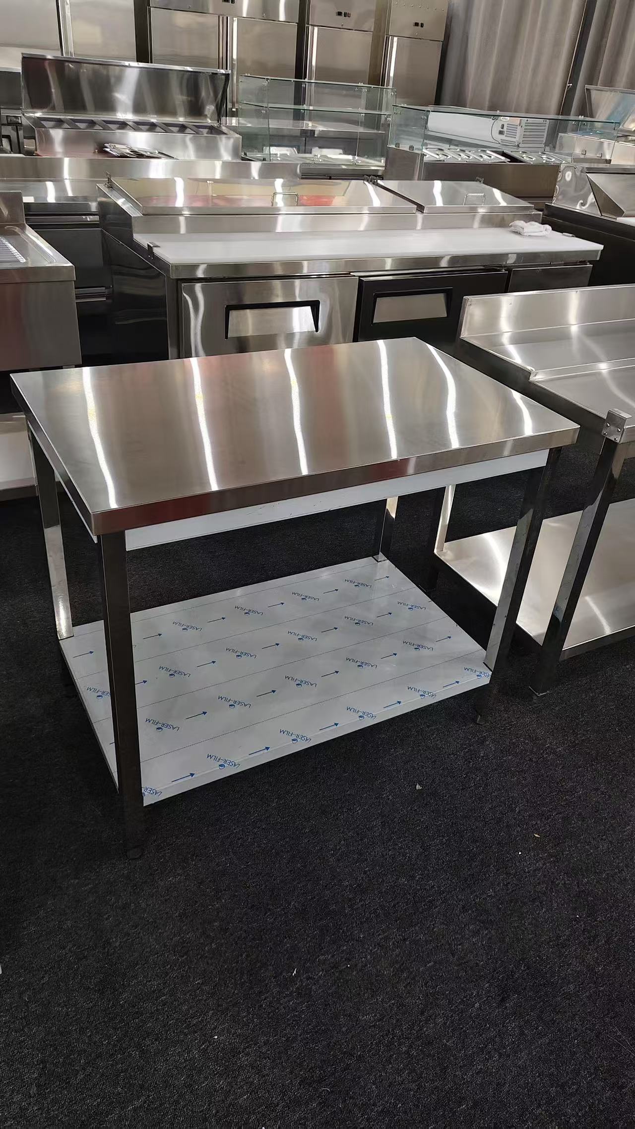 Stainless steel worktable with undershelf photographed with protective film in a partner workshop