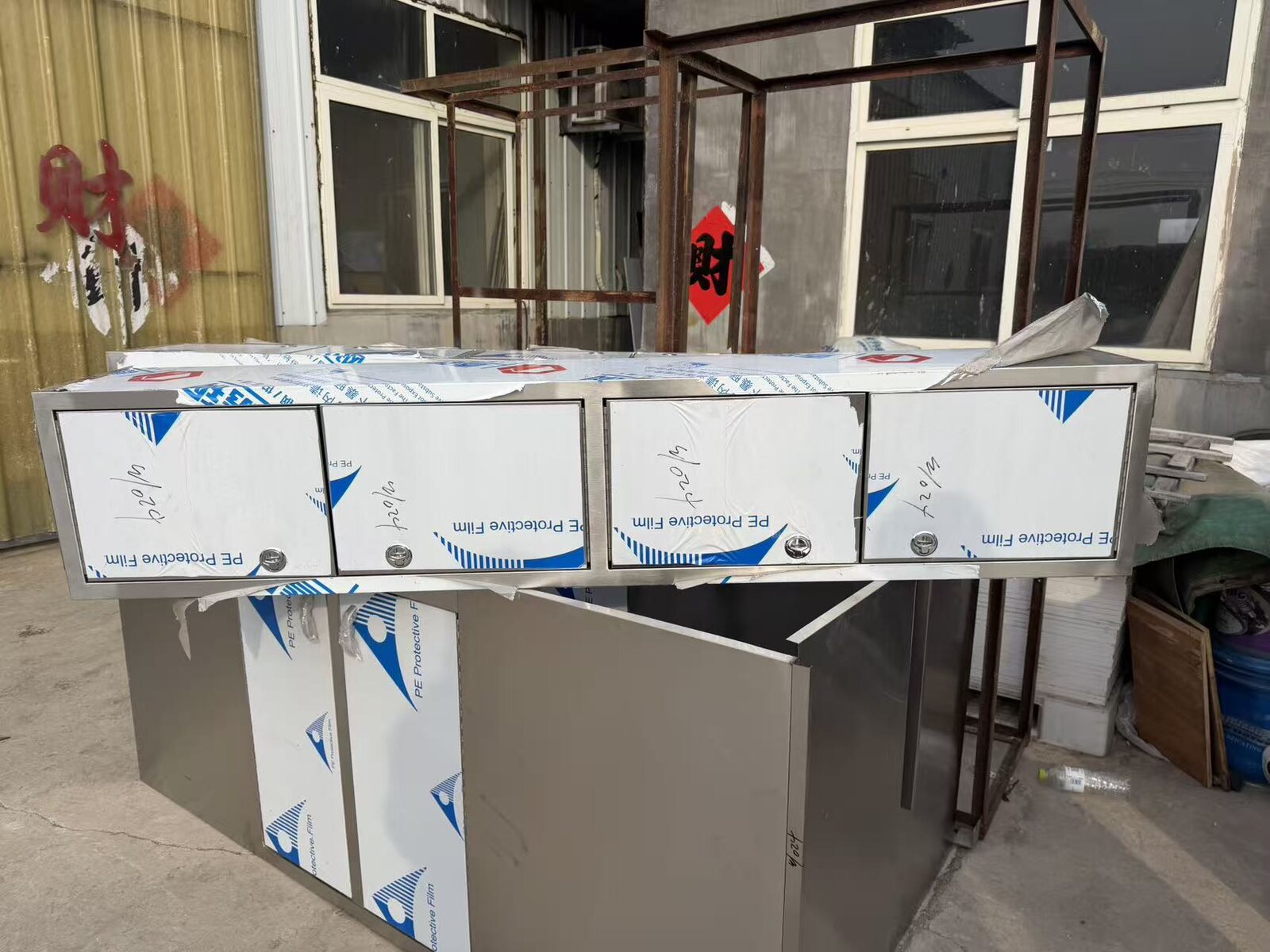 Stainless steel wall cabinet units photographed under protective film in a partner workshop