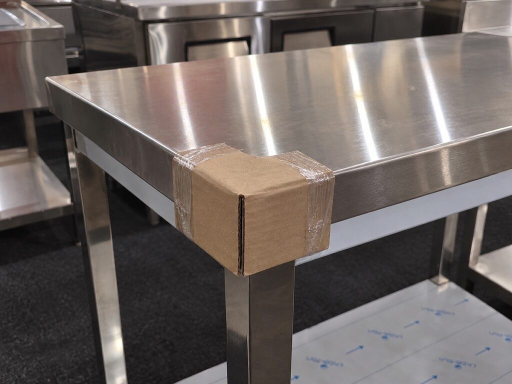 Illustrative close-up of a cardboard protector on a stainless worktable corner